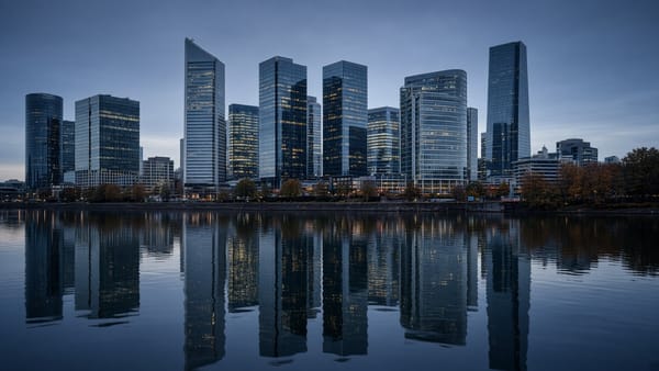 Skyline mit Glastürmen, die sich zur blauen Stunde in einem Fluss spiegelt